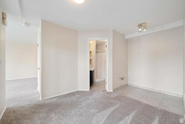spare room featuring light tile patterned floors, baseboards, and light carpet