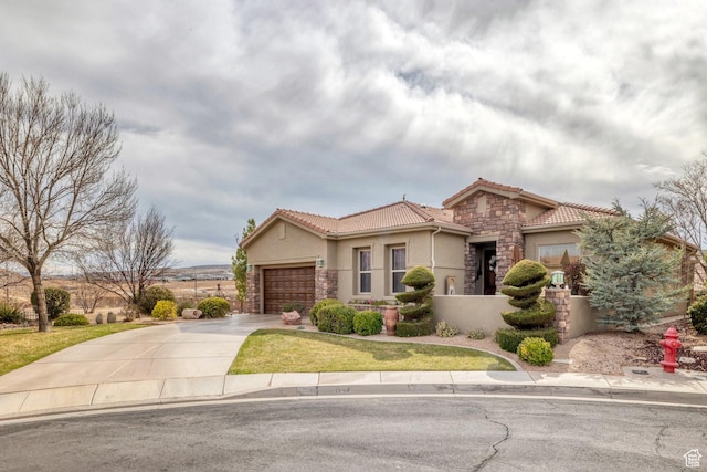 mediterranean / spanish home with a tiled roof, stone siding, an attached garage, and concrete driveway
