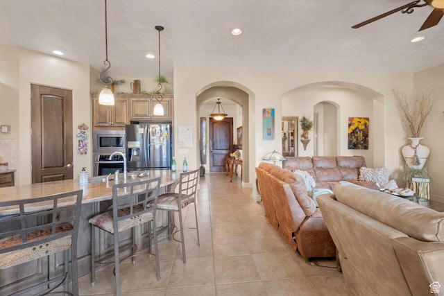living area with arched walkways, light tile patterned floors, recessed lighting, and ceiling fan