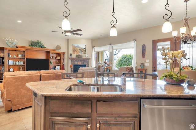 kitchen with ceiling fan with notable chandelier, a sink, light stone counters, stainless steel dishwasher, and light tile patterned flooring
