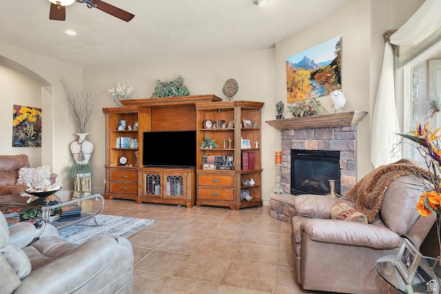 living area with light tile patterned floors, recessed lighting, a fireplace, arched walkways, and a ceiling fan