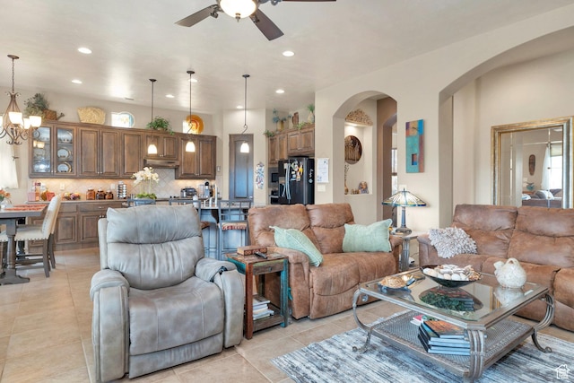 living room with recessed lighting, arched walkways, light tile patterned floors, and ceiling fan with notable chandelier