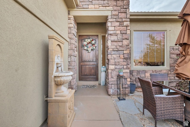 view of exterior entry with stucco siding and stone siding