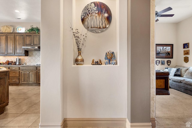 hallway featuring light tile patterned floors, visible vents, baseboards, and light carpet