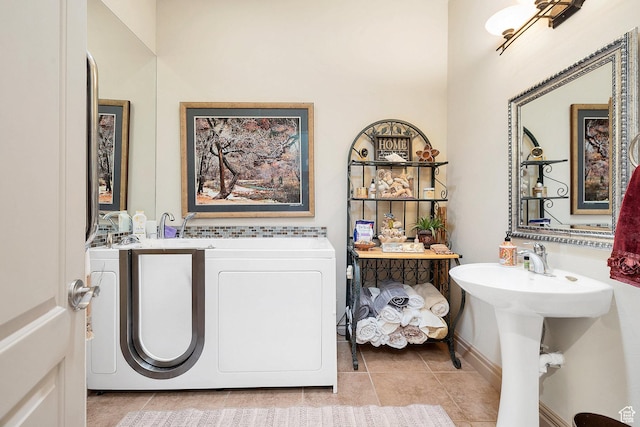 bathroom with tile patterned flooring, a sink, a bathtub, and washer and clothes dryer