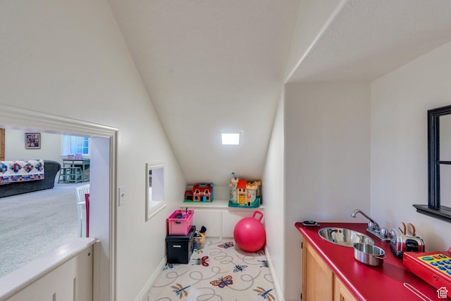 recreation room featuring lofted ceiling, carpet, baseboards, and a sink