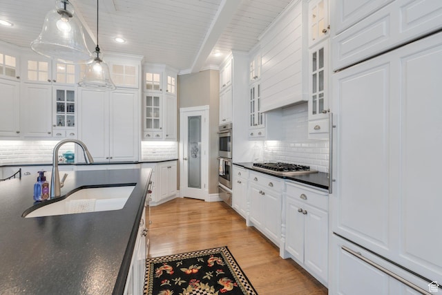 kitchen with dark countertops, white cabinetry, stainless steel appliances, and a sink