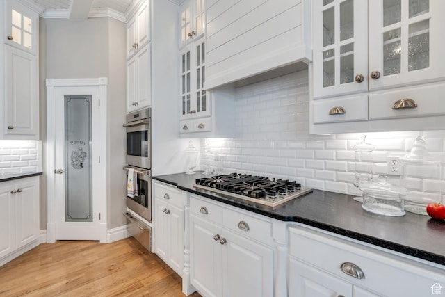 kitchen featuring dark countertops, a warming drawer, white cabinets, and appliances with stainless steel finishes