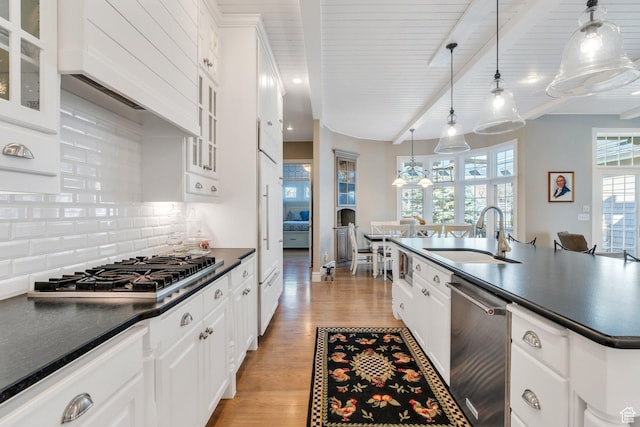 kitchen with dark countertops, light wood-style floors, appliances with stainless steel finishes, and a sink