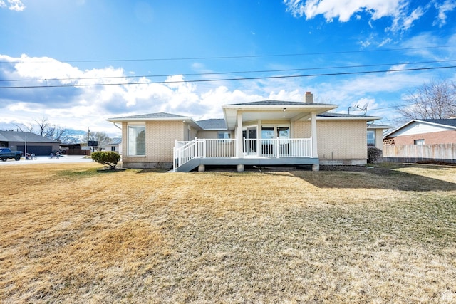 view of front of house featuring a wooden deck, a chimney, a front yard, and fence