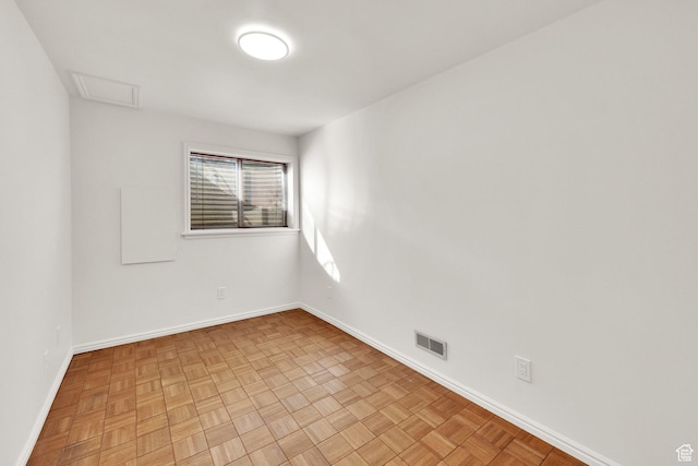 empty room featuring visible vents, attic access, and baseboards