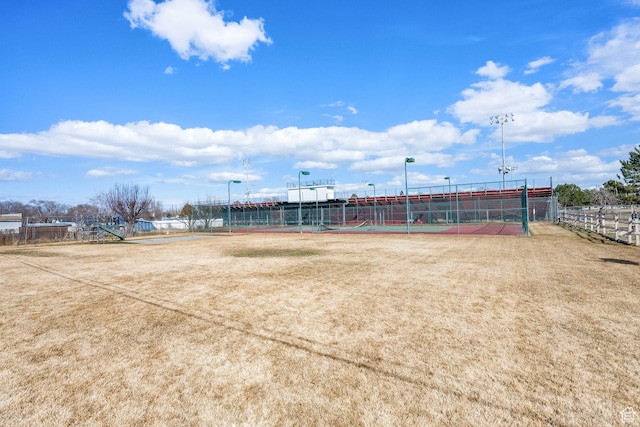 view of home's community with a tennis court and fence