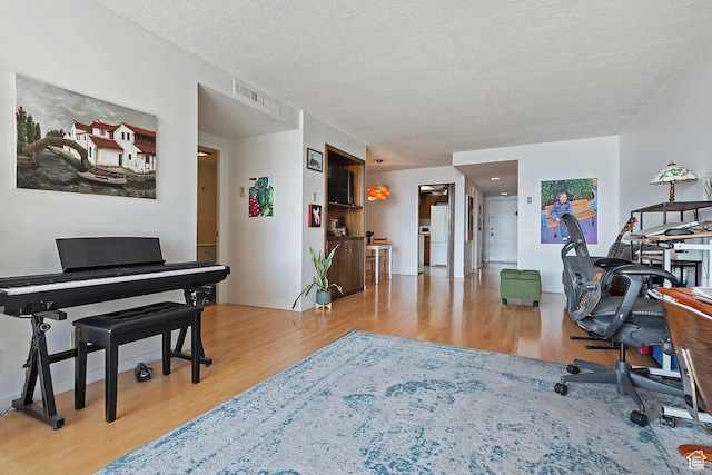 office area featuring wood finished floors, visible vents, and a textured ceiling