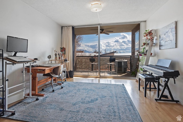 office area featuring a ceiling fan, floor to ceiling windows, wood finished floors, and a textured ceiling