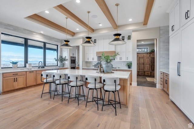 1413 N 1500 E, Provo, UT 84604 - kitchen featuring a breakfast bar, light wood-style flooring, tasteful backsplash, stainless steel double oven, and a large island with sink