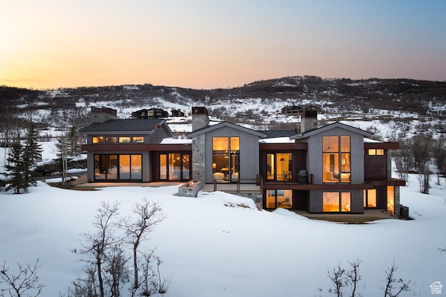 snow covered property with a mountain view and a chimney