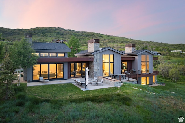 9774 N Red Hawk Trl, Park City, UT 84098 - back of house at dusk with a chimney, a patio, and a yard