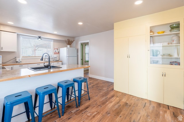 kitchen featuring light wood-style flooring, recessed lighting, freestanding refrigerator, a sink, and a kitchen bar