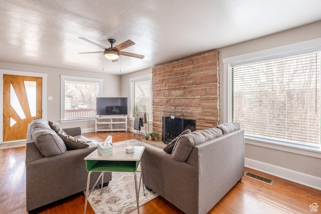 living room featuring ceiling fan, visible vents, and wood finished floors