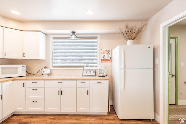 kitchen with light wood finished floors, white appliances, light countertops, and white cabinetry