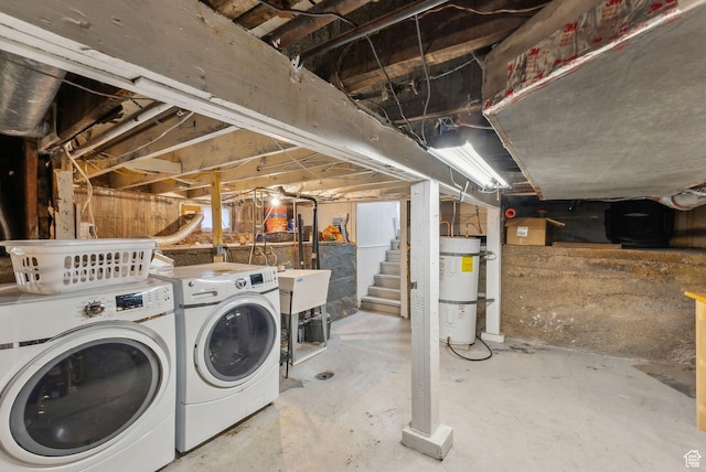 unfinished below grade area with a sink, washer and clothes dryer, and strapped water heater