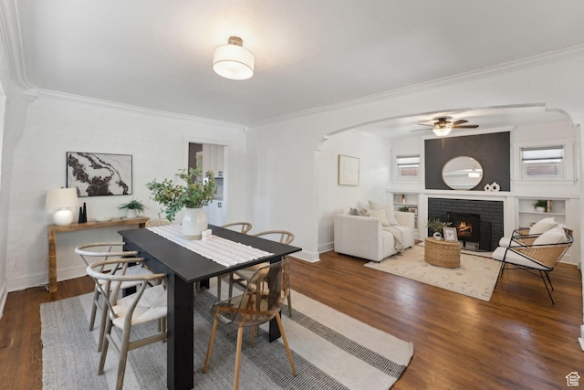 dining space with arched walkways, ornamental molding, a ceiling fan, and wood finished floors