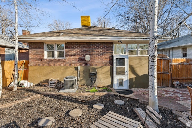 back of property featuring a chimney, a gate, brick siding, fence, and cooling unit