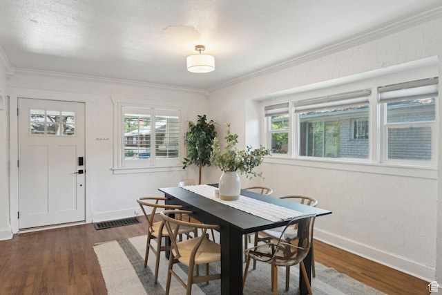 dining space featuring baseboards, crown molding, wood finished floors, and visible vents