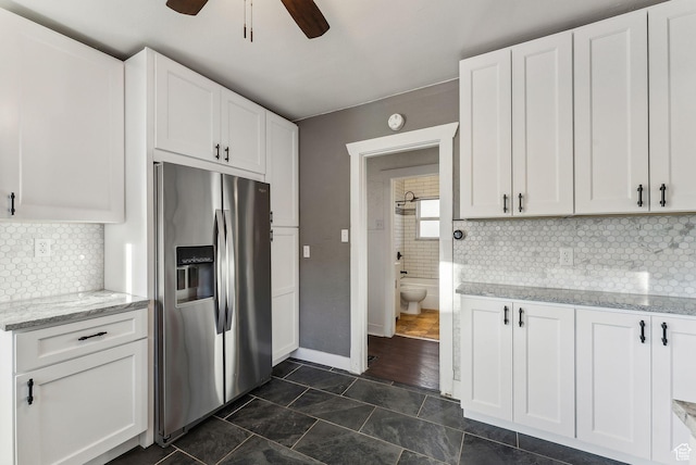 kitchen featuring ceiling fan, backsplash, light stone countertops, stainless steel fridge with ice dispenser, and white cabinets