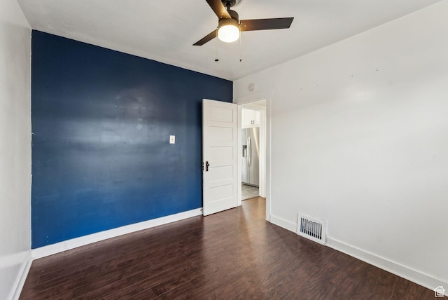 spare room with baseboards, ceiling fan, visible vents, and wood finished floors