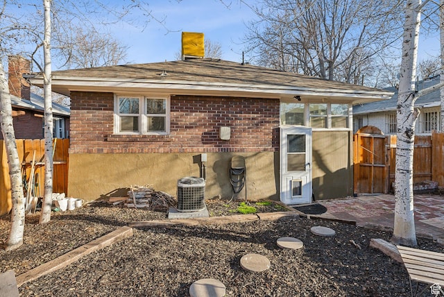 rear view of property featuring fence, a chimney, brick siding, a gate, and central air condition unit