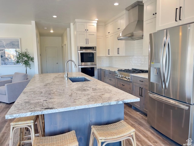 833 W Sunrise Cir, Garden City, UT 84028 - kitchen with wood finished floors, appliances with stainless steel finishes, a sink, light stone counters, and wall chimney range hood