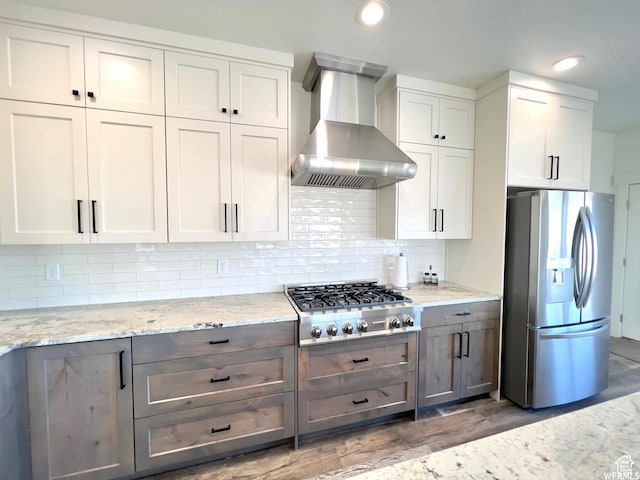 833 W Sunrise Cir, Garden City, UT 84028 - kitchen featuring light stone counters, backsplash, wall chimney exhaust hood, light wood-type flooring, and stainless steel appliances
