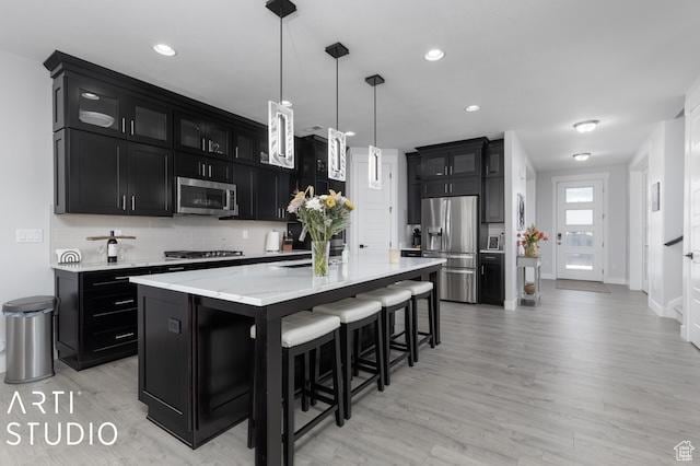 2211 W Parkview Dr, Syracuse, UT 84075 - kitchen featuring light wood finished floors, light countertops, appliances with stainless steel finishes, a kitchen breakfast bar, and dark cabinetry