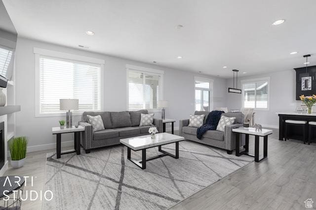 2211 W Parkview Dr, Syracuse, UT 84075 - living room featuring recessed lighting, baseboards, a glass covered fireplace, and light wood-style flooring