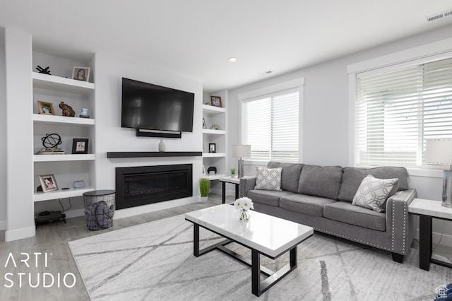2211 W Parkview Dr, Syracuse, UT 84075 - living area with built in features, visible vents, a glass covered fireplace, and wood finished floors