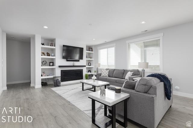 2211 W Parkview Dr, Syracuse, UT 84075 - living room featuring a fireplace, built in features, light wood-style floors, and baseboards