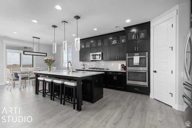 2211 W Parkview Dr, Syracuse, UT 84075 - kitchen featuring a breakfast bar, stainless steel appliances, light wood-style floors, light countertops, and dark cabinets