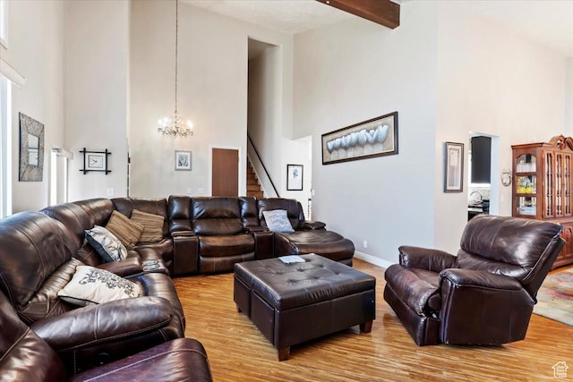 living area with light wood finished floors, an inviting chandelier, a high ceiling, beam ceiling, and stairs