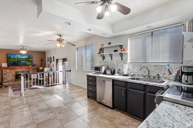 kitchen featuring stainless steel dishwasher, a ceiling fan, tasteful backsplash, and a sink