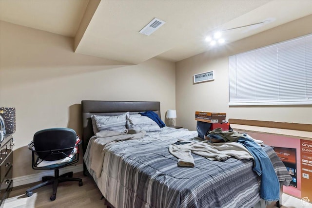 bedroom with visible vents, baseboards, and wood finished floors