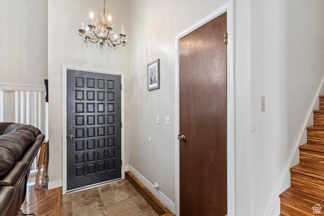 foyer featuring baseboards, a chandelier, and stairs