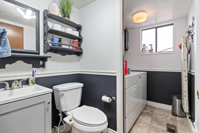 bathroom featuring visible vents, toilet, washing machine and dryer, baseboards, and vanity