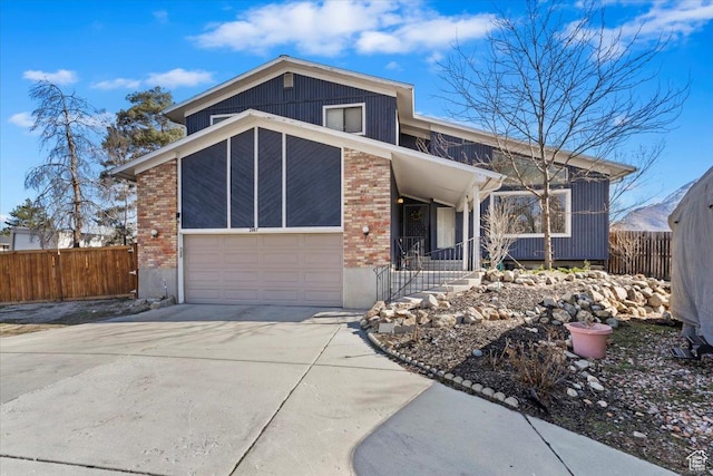mid-century inspired home featuring concrete driveway, an attached garage, fence, and brick siding