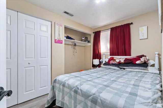 bedroom with visible vents, a closet, and wood finished floors