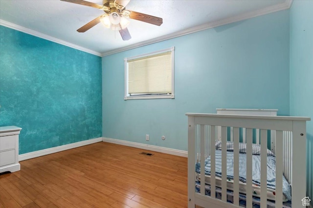 bedroom with ceiling fan, crown molding, baseboards, and wood finished floors