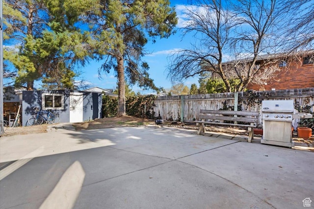view of patio / terrace with an outdoor structure, a fenced backyard, and a grill