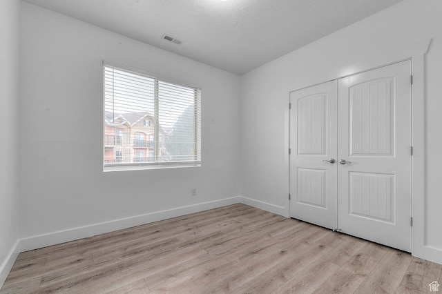 unfurnished bedroom with light wood-type flooring, visible vents, a closet, and baseboards