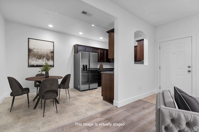 kitchen featuring dark brown cabinetry, baseboards, stainless steel fridge, recessed lighting, and visible vents
