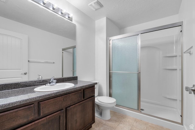 full bathroom with vanity, a stall shower, tile patterned flooring, a textured ceiling, and toilet
